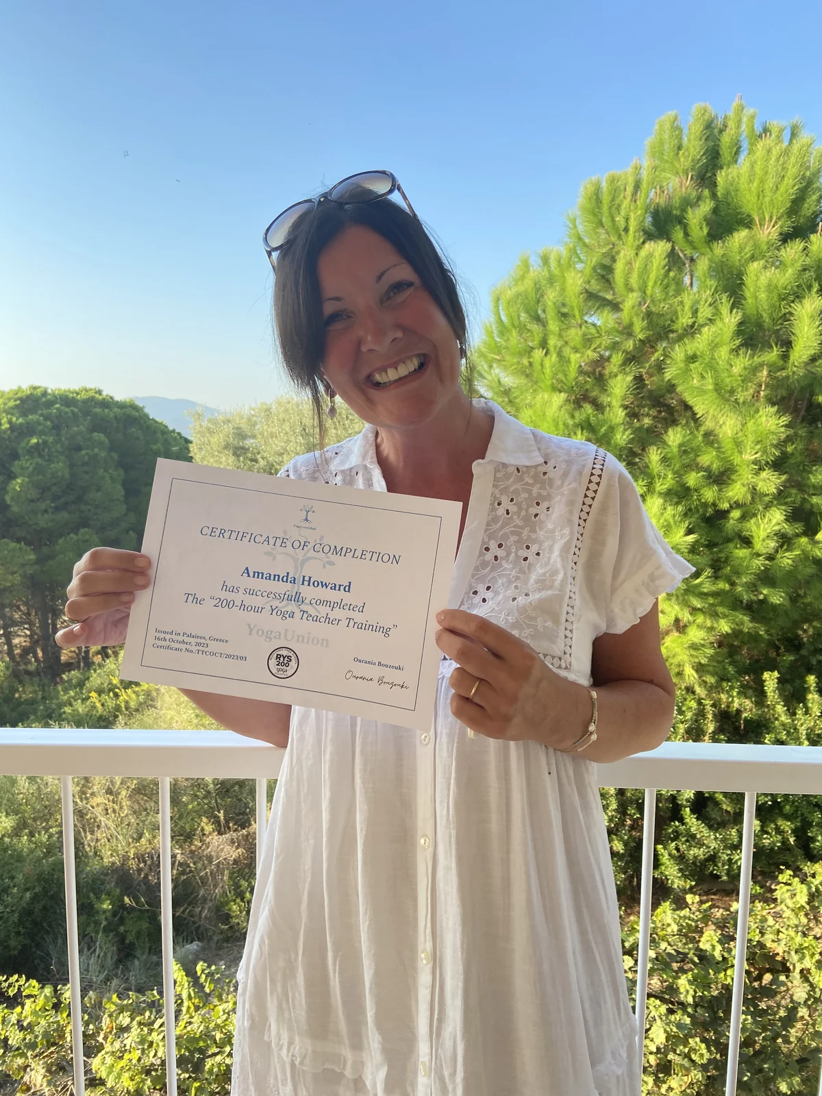Amanda smiling and holding her yoga teacher training certificate