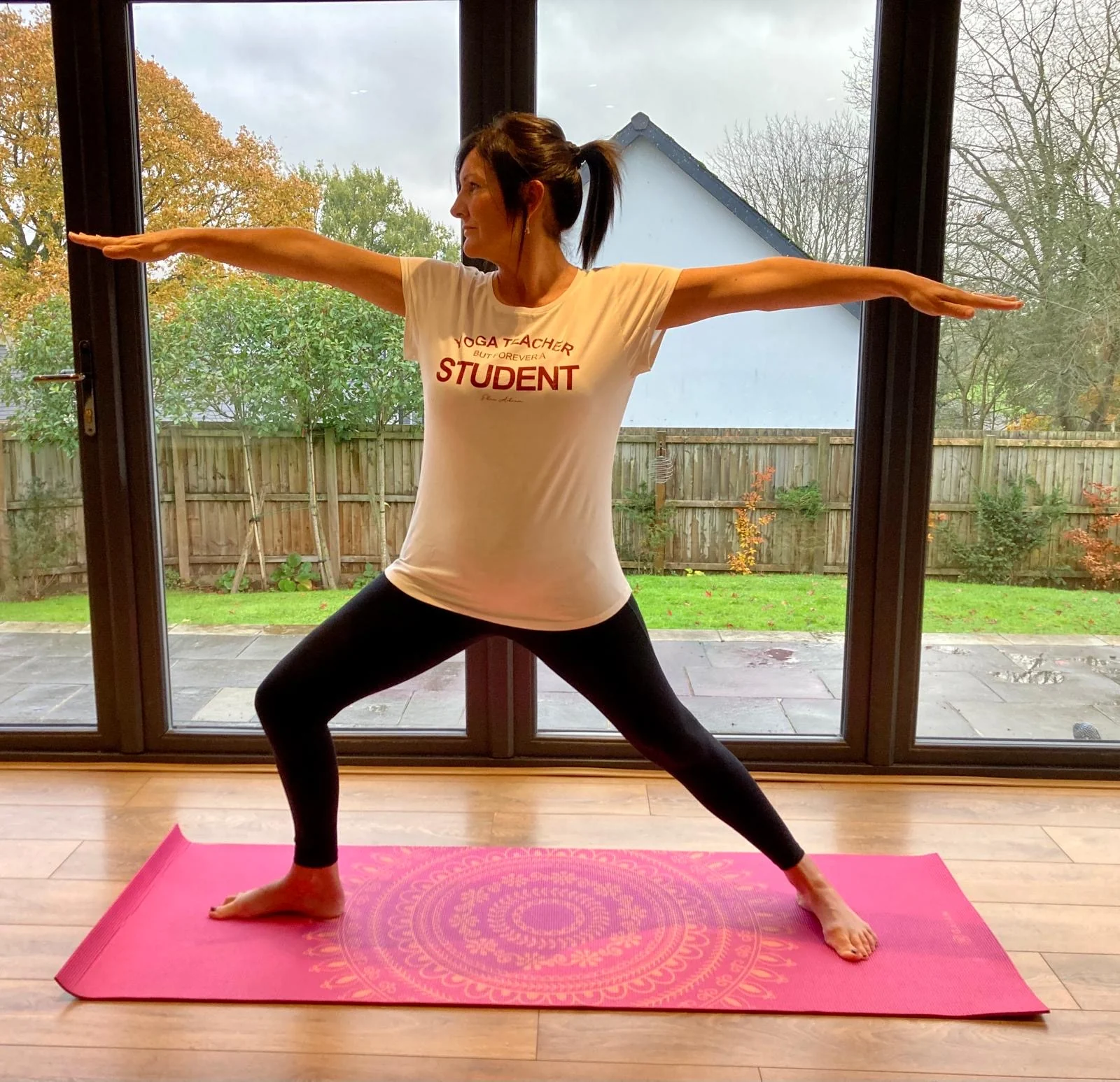 Amanda demonstrating a Hatha yoga warrior pose on a yoga mat